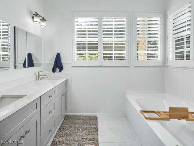 114 Amblewood Ln Unit 9-903, Naples, FL 34105 - full bathroom featuring double vanity, a garden tub, wainscoting, and marble look tile flooring