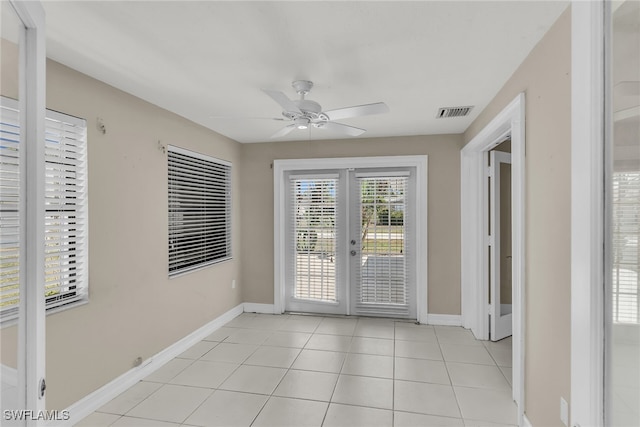 interior space with visible vents, light tile patterned floors, baseboards, ceiling fan, and french doors