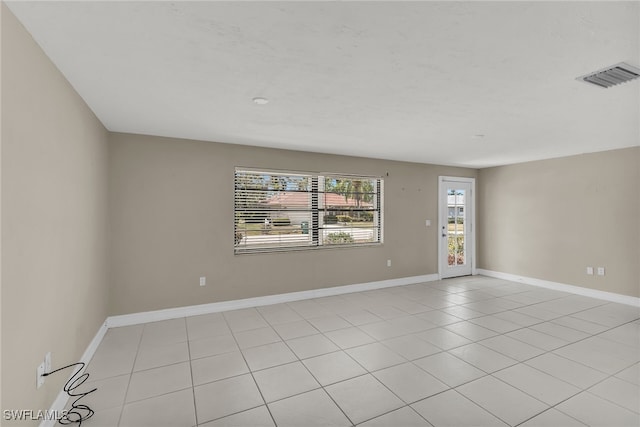 empty room featuring light tile patterned floors, visible vents, and baseboards