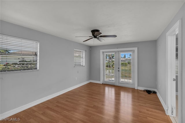 empty room featuring french doors, light wood finished floors, baseboards, and a ceiling fan