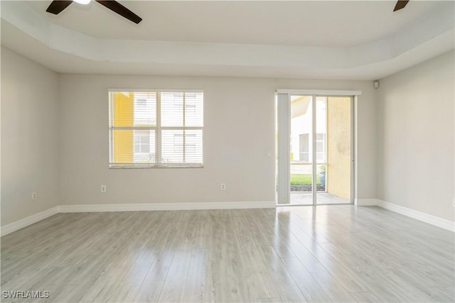 spare room with light wood-style flooring, baseboards, a ceiling fan, and a healthy amount of sunlight
