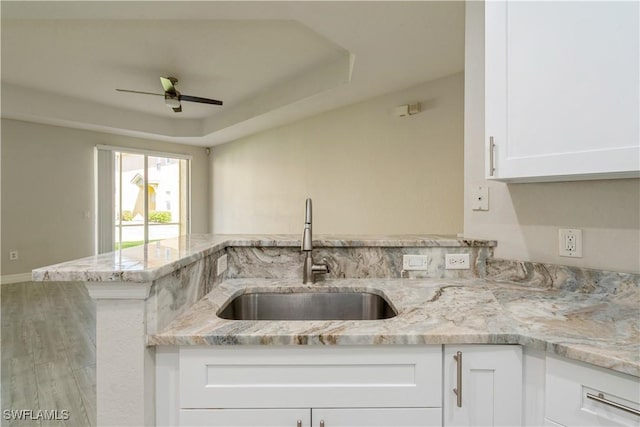 kitchen featuring light stone countertops, ceiling fan, a sink, and white cabinets