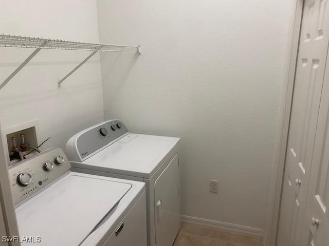 laundry room featuring washer and dryer, baseboards, laundry area, and light tile patterned floors