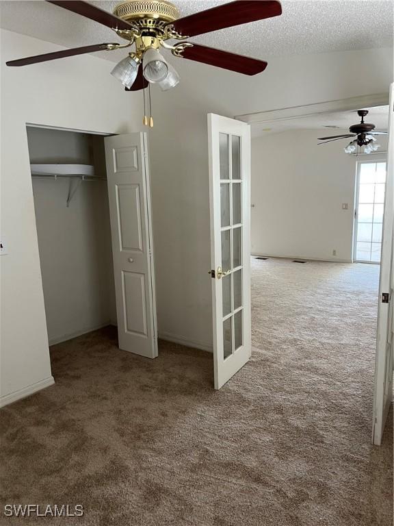 901 Thatcher Blvd, Moore Haven, FL 33471 - unfurnished bedroom featuring carpet flooring, french doors, a textured ceiling, a closet, and a ceiling fan