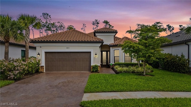 mediterranean / spanish-style home with a tiled roof, an attached garage, decorative driveway, and stucco siding