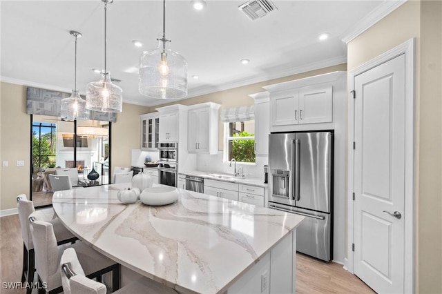 kitchen with visible vents, a sink, a breakfast bar, light wood-style floors, and stainless steel appliances