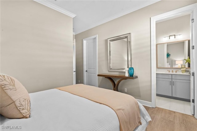 bedroom with baseboards, ensuite bath, light wood-style flooring, crown molding, and a sink