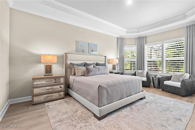 bedroom with wood finished floors, baseboards, ornamental molding, and a raised ceiling