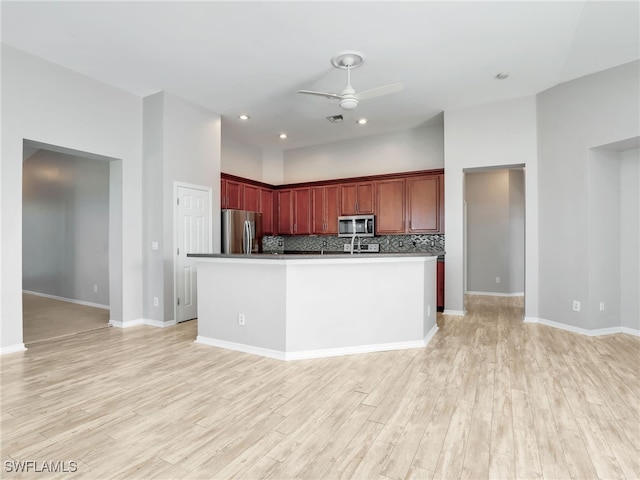 17274 Asmara Ct, Punta Gorda, FL 33955 - kitchen with appliances with stainless steel finishes, ceiling fan, light wood-style floors, reddish brown cabinets, and decorative backsplash