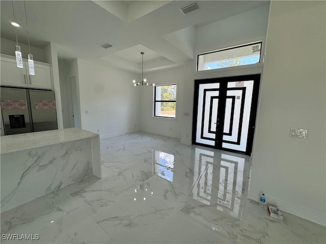 foyer entrance with visible vents, marble finish floor, a raised ceiling, baseboards, and a notable chandelier