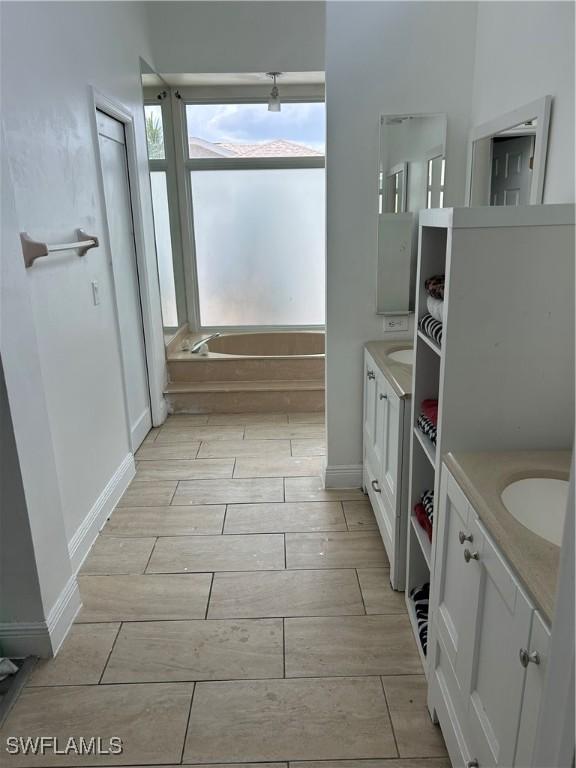 8860 Banyan Cove Cir S Unit 0, Fort Myers, FL 33919 - bathroom with two vanities, wood tiled floors, a garden tub, and baseboards