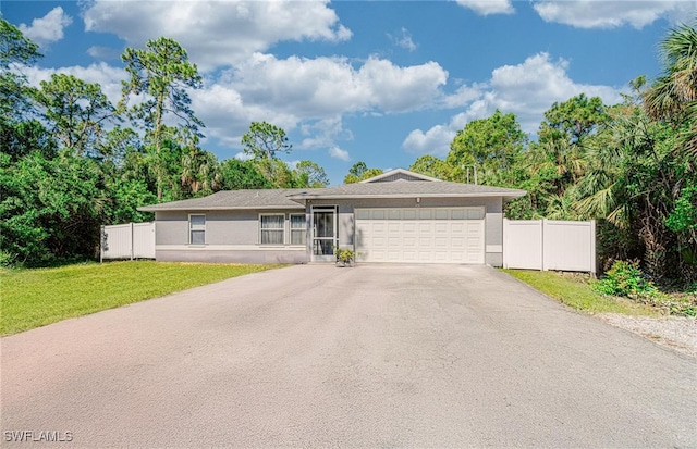 ranch-style home with an attached garage, driveway, a front yard, and fence
