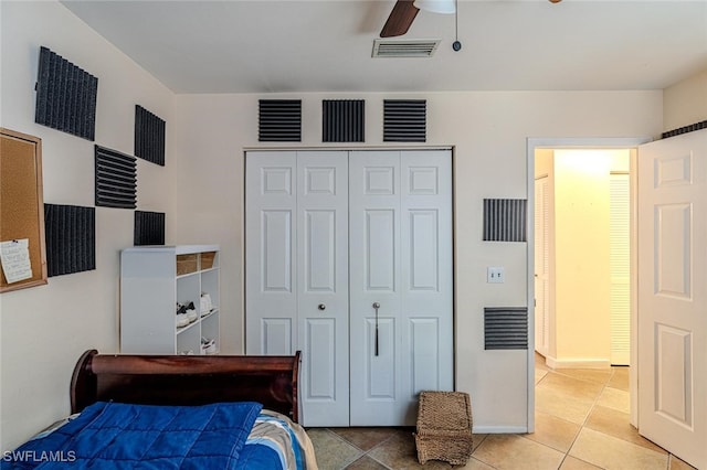 bedroom with a ceiling fan, light tile patterned flooring, visible vents, and a closet