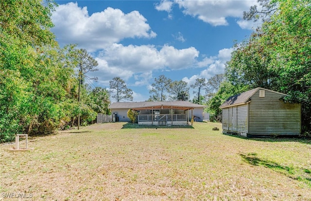 rear view of property featuring a lawn, an outdoor structure, a sunroom, and a shed