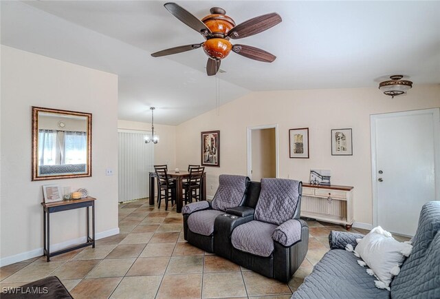 living room featuring baseboards, vaulted ceiling, light tile patterned floors, and ceiling fan with notable chandelier