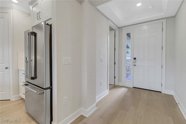 foyer with recessed lighting, baseboards, a tray ceiling, and light wood-type flooring