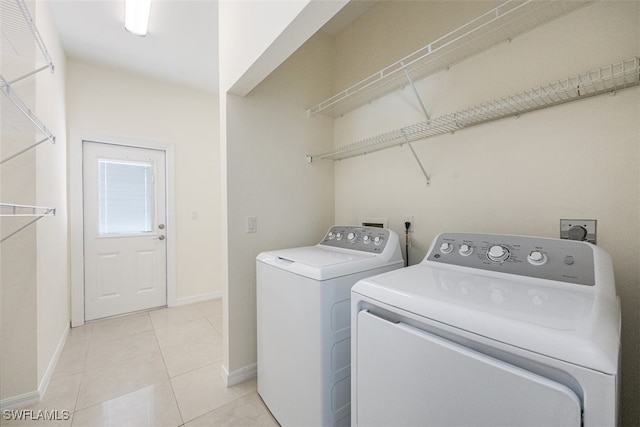 washroom with baseboards, washer and dryer, laundry area, and light tile patterned flooring