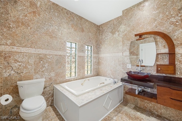 bathroom with tile walls, a bath, vanity, and toilet