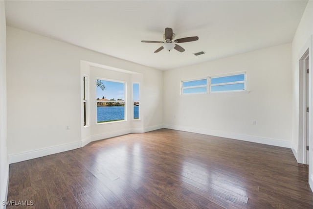 spare room with wood finished floors, visible vents, a ceiling fan, and baseboards