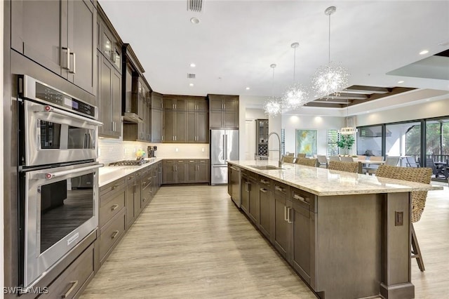 16358 Corsica Way Unit 201, Naples, FL 34110 - kitchen featuring a sink, stainless steel appliances, dark brown cabinets, light wood-style flooring, and recessed lighting