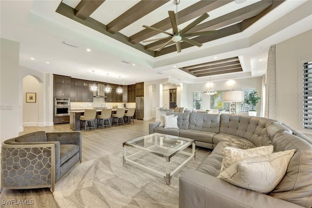 16358 Corsica Way Unit 201, Naples, FL 34110 - living room with ceiling fan, a tray ceiling, arched walkways, recessed lighting, and light wood finished floors