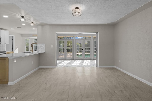 interior space featuring a sink, french doors, a textured ceiling, and a wealth of natural light
