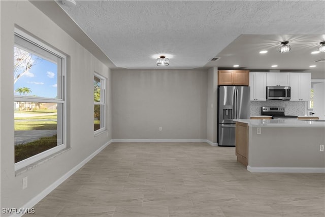 kitchen featuring appliances with stainless steel finishes, light countertops, a textured ceiling, tasteful backsplash, and visible vents