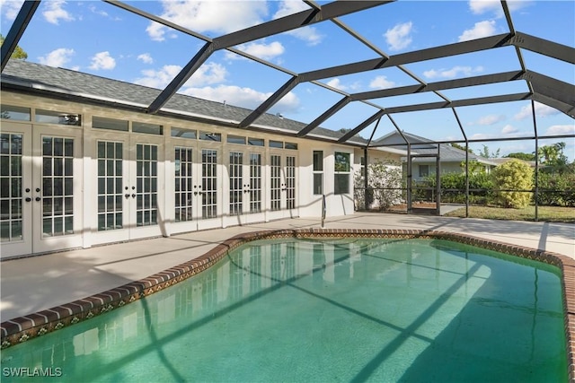 outdoor pool featuring a patio, glass enclosure, and french doors