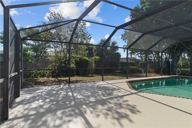 outdoor pool featuring glass enclosure and a patio area