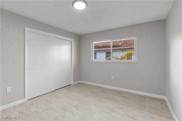 unfurnished bedroom featuring baseboards and a closet