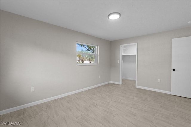unfurnished bedroom featuring baseboards and a spacious closet