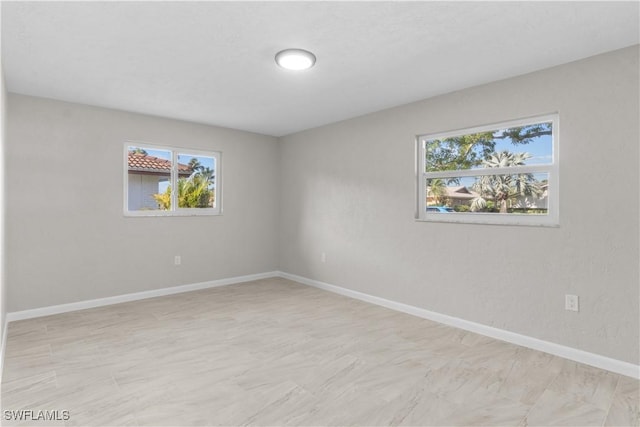 unfurnished room featuring baseboards and plenty of natural light