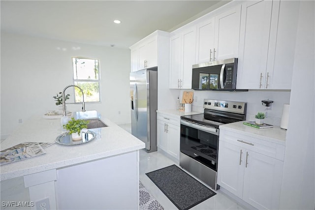 kitchen featuring stainless steel appliances, white cabinets, light countertops, recessed lighting, and a sink