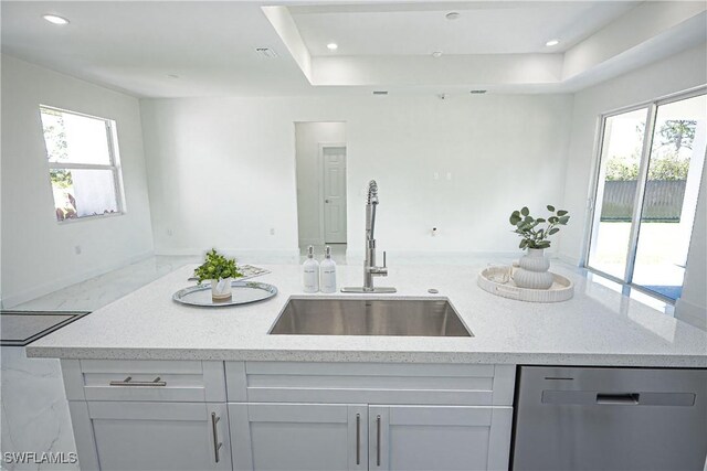 kitchen with dishwasher, a sink, light stone counters, plenty of natural light, and recessed lighting