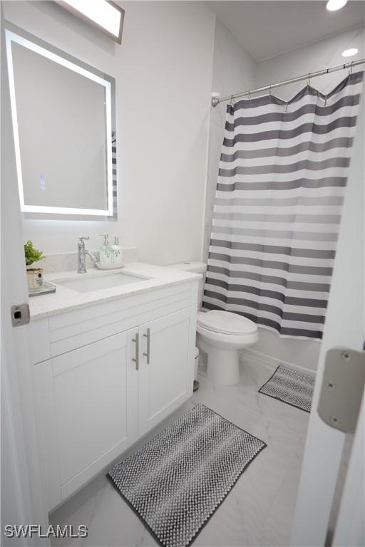 full bathroom with marble look tiles, vanity, and toilet