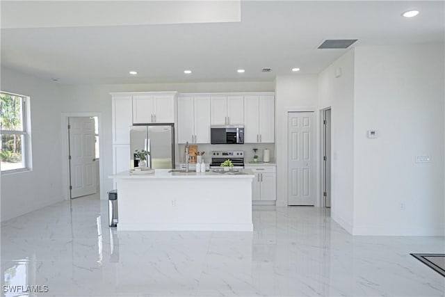 kitchen with stainless steel appliances, white cabinets, a kitchen island with sink, recessed lighting, and baseboards