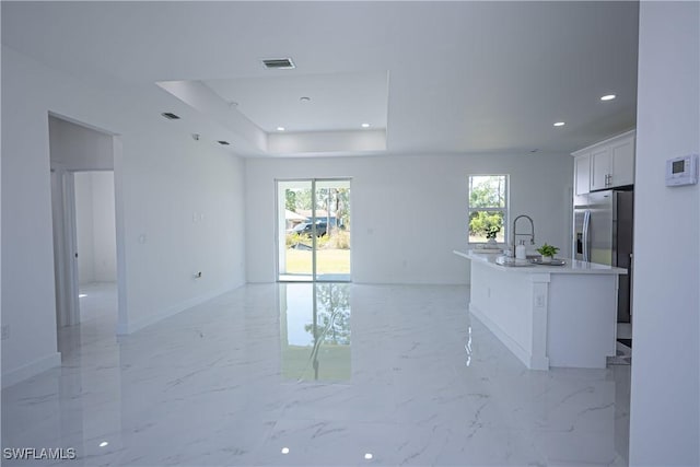 living area with baseboards, recessed lighting, light marble finish floors, and a raised ceiling