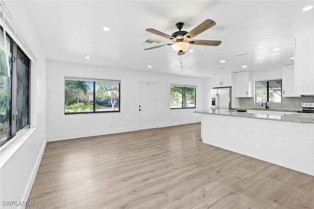 3433 Hibiscus Ave, Naples, FL 34104 - unfurnished living room with light wood finished floors, visible vents, a ceiling fan, and a healthy amount of sunlight
