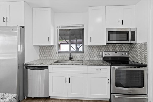 3433 Hibiscus Ave, Naples, FL 34104 - kitchen with white cabinetry, appliances with stainless steel finishes, light stone counters, a sink, and decorative backsplash