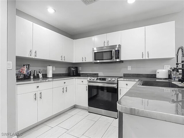 2732 NW 3rd Ter, Cape Coral, FL 33993 - kitchen with white cabinets, a sink, and appliances with stainless steel finishes