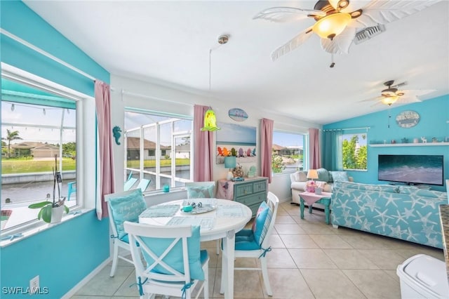 dining room with ceiling fan, vaulted ceiling, tile patterned flooring, and visible vents