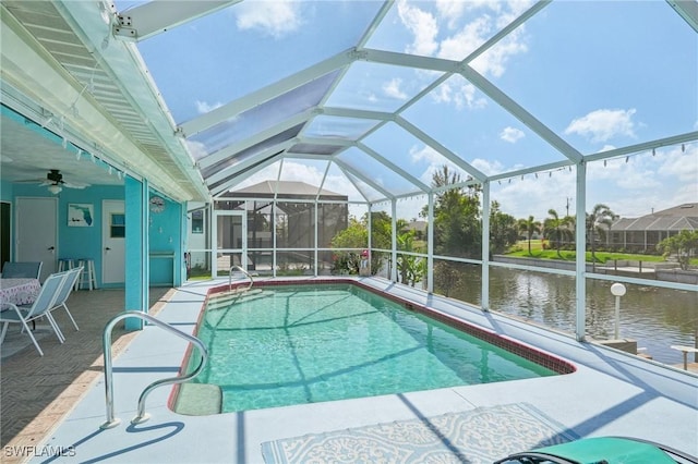 pool with a water view, a ceiling fan, a patio, and glass enclosure