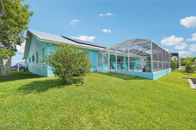 rear view of house featuring a lanai, roof mounted solar panels, a lawn, and stucco siding
