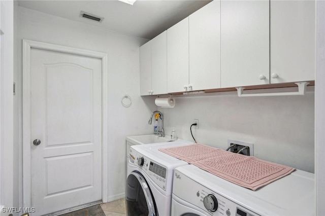 laundry room featuring visible vents, light tile patterned floors, separate washer and dryer, a sink, and cabinet space