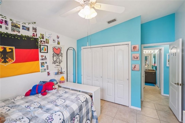 bedroom featuring lofted ceiling, a closet, light tile patterned floors, visible vents, and ceiling fan
