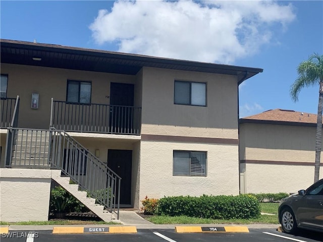 view of property with stairs and uncovered parking