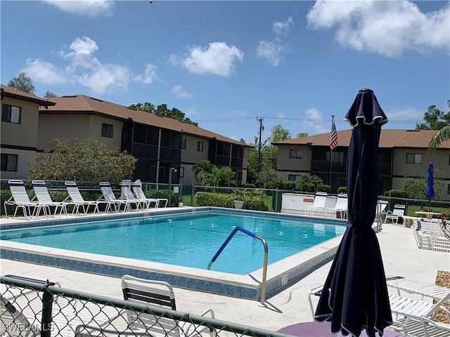 community pool with a patio area and fence