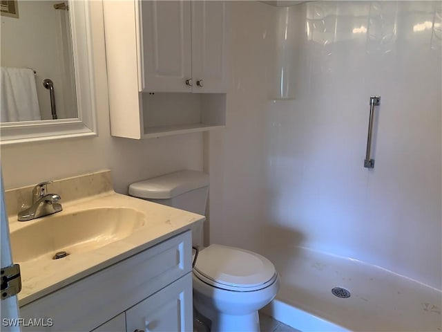 bathroom with toilet, a stall shower, and vanity