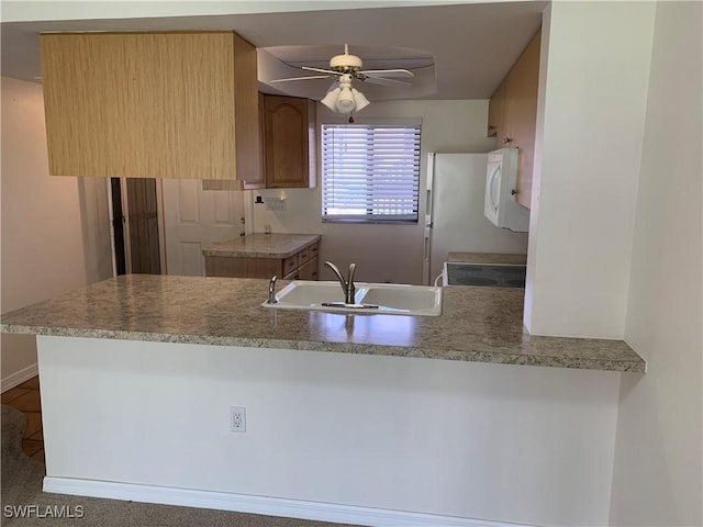 kitchen featuring a sink, a ceiling fan, a peninsula, white microwave, and range