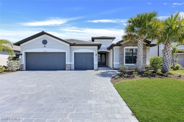 11477 Canopy Loop, Fort Myers, FL 33913 - view of front of property with stone siding, stucco siding, a garage, decorative driveway, and a front lawn